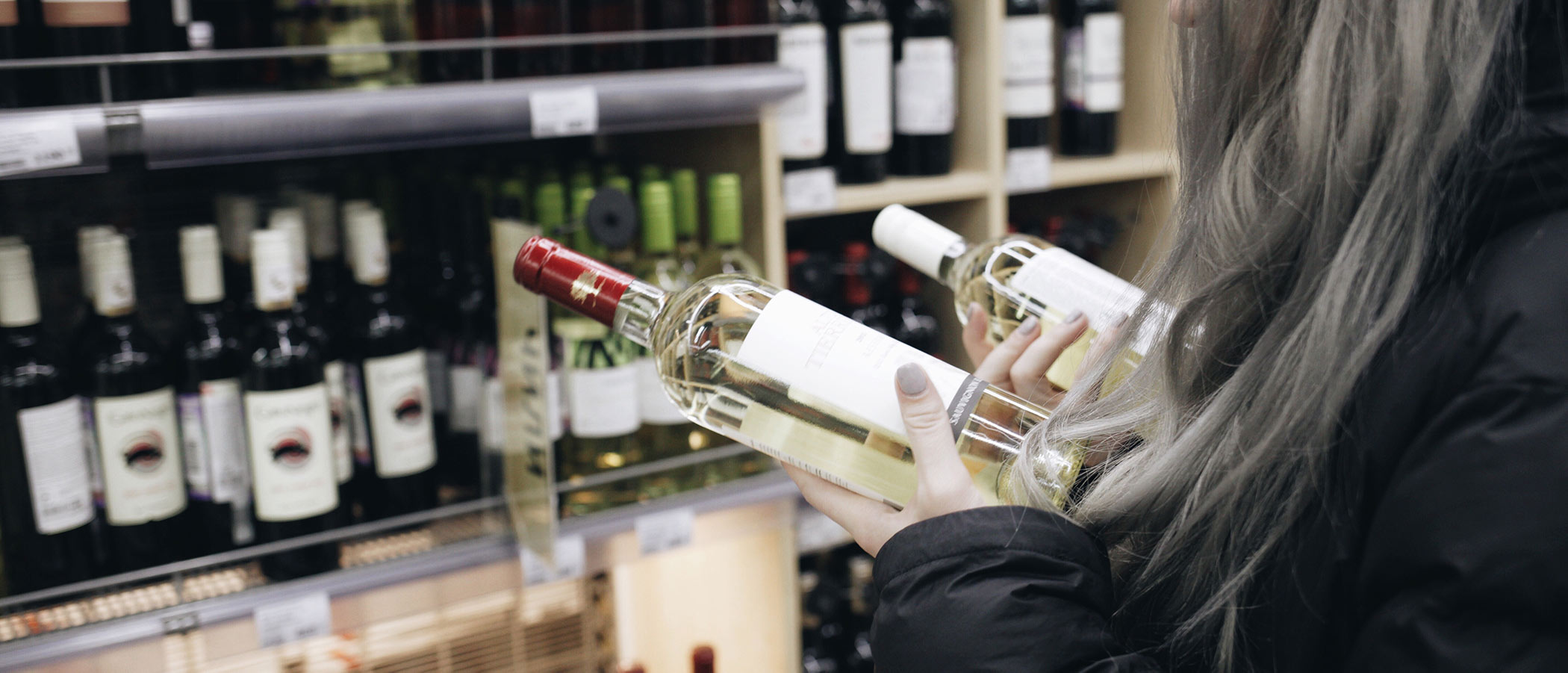 Woman choosing wine at the grocery store