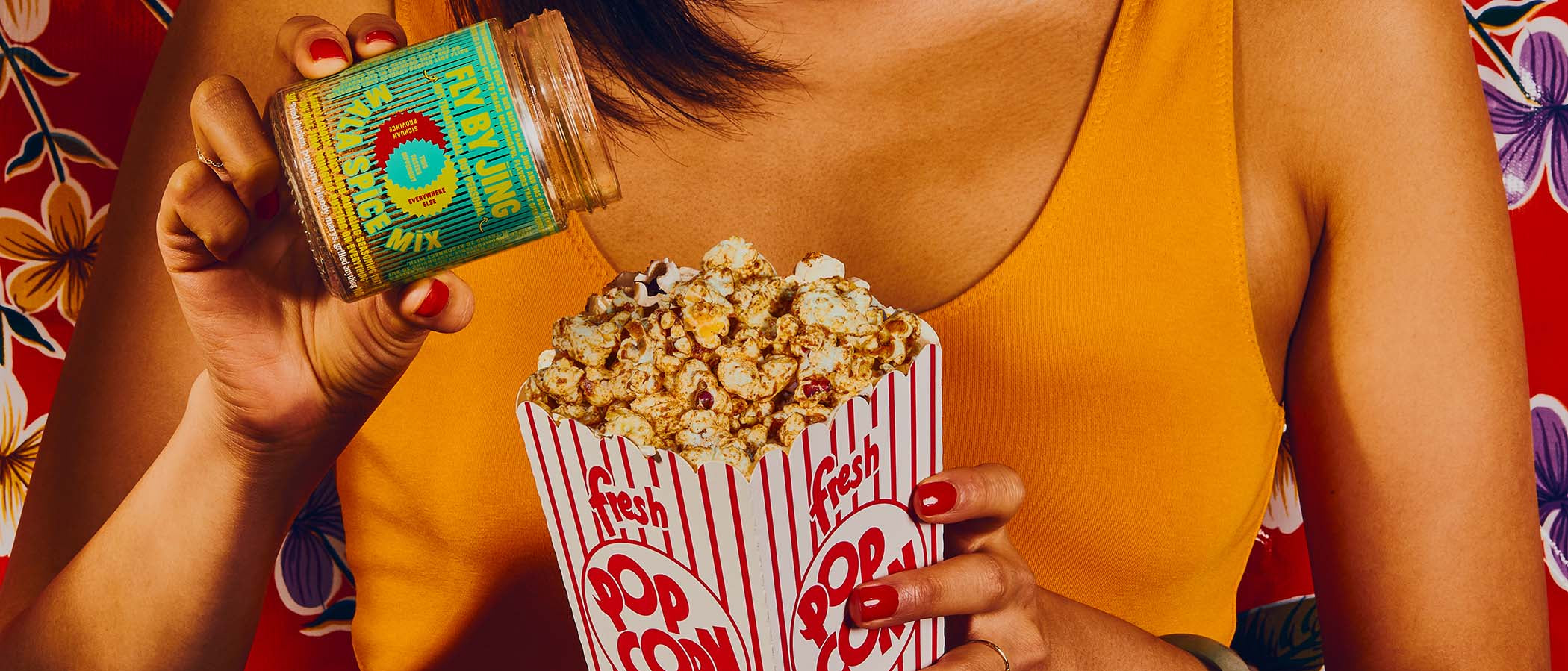 Close up of woman seasoning popcorn with Fly By Jing Mala Spice Mix