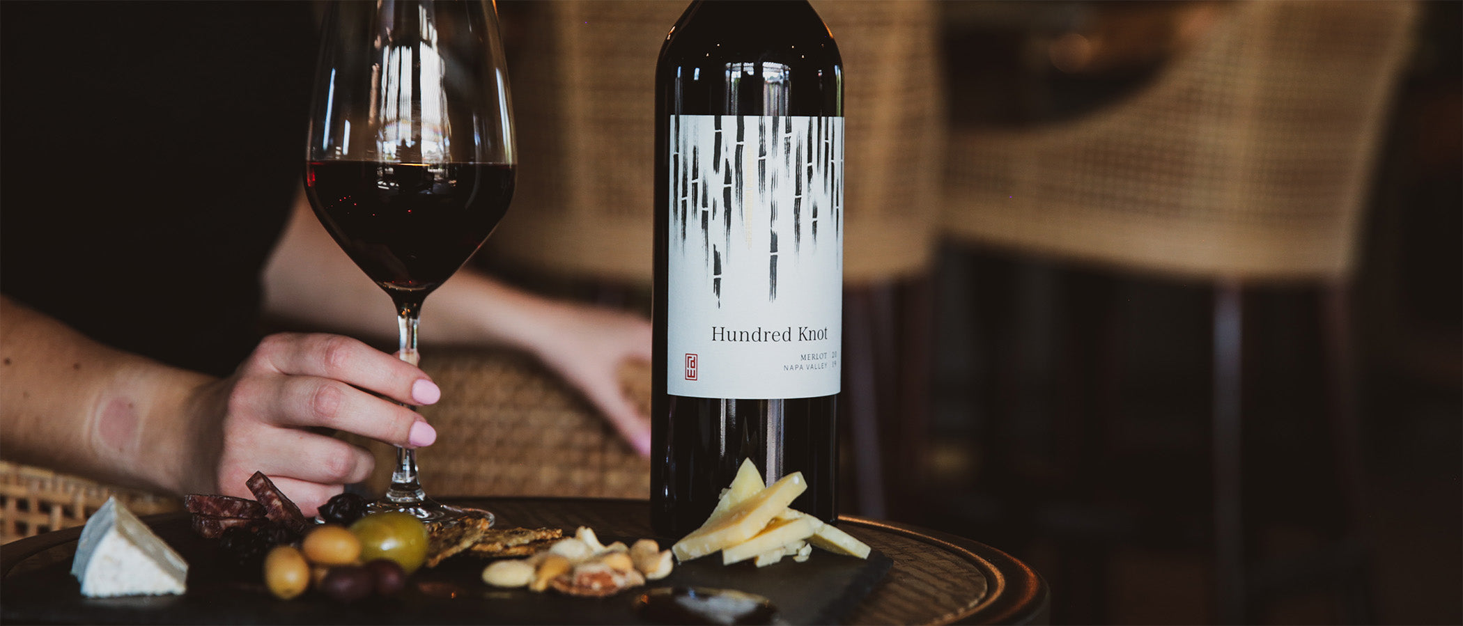 Glass of red, bottle of Merlot, and cheese plate