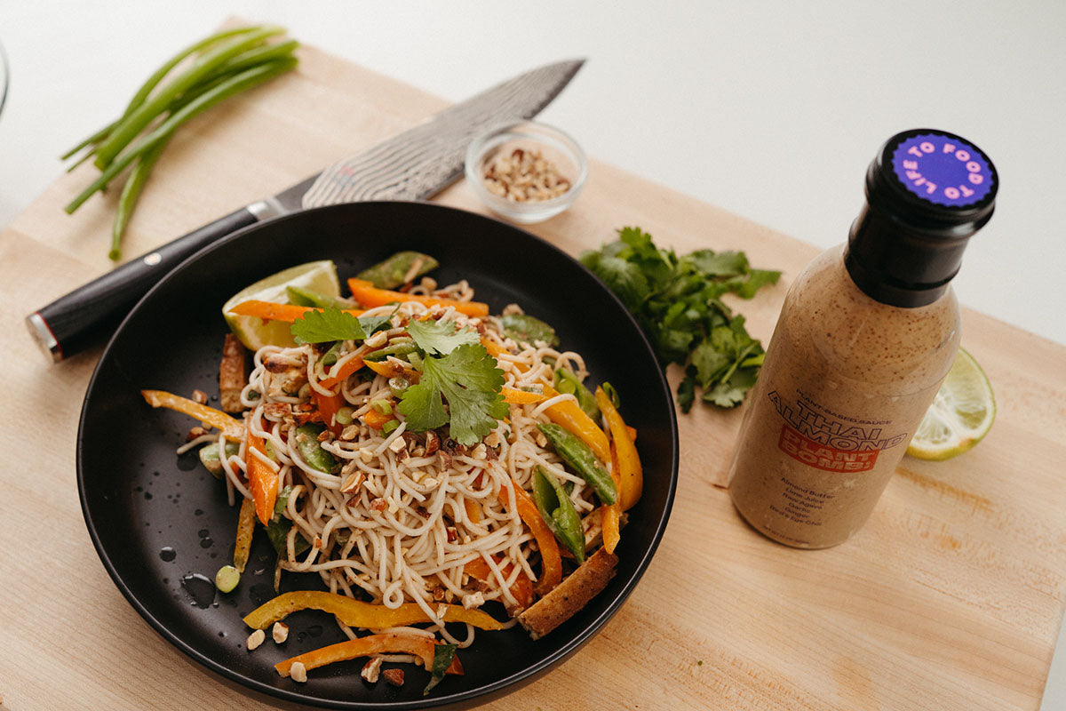 Thai Almond Cold Noodle Salad in bowl with sauce next to it.