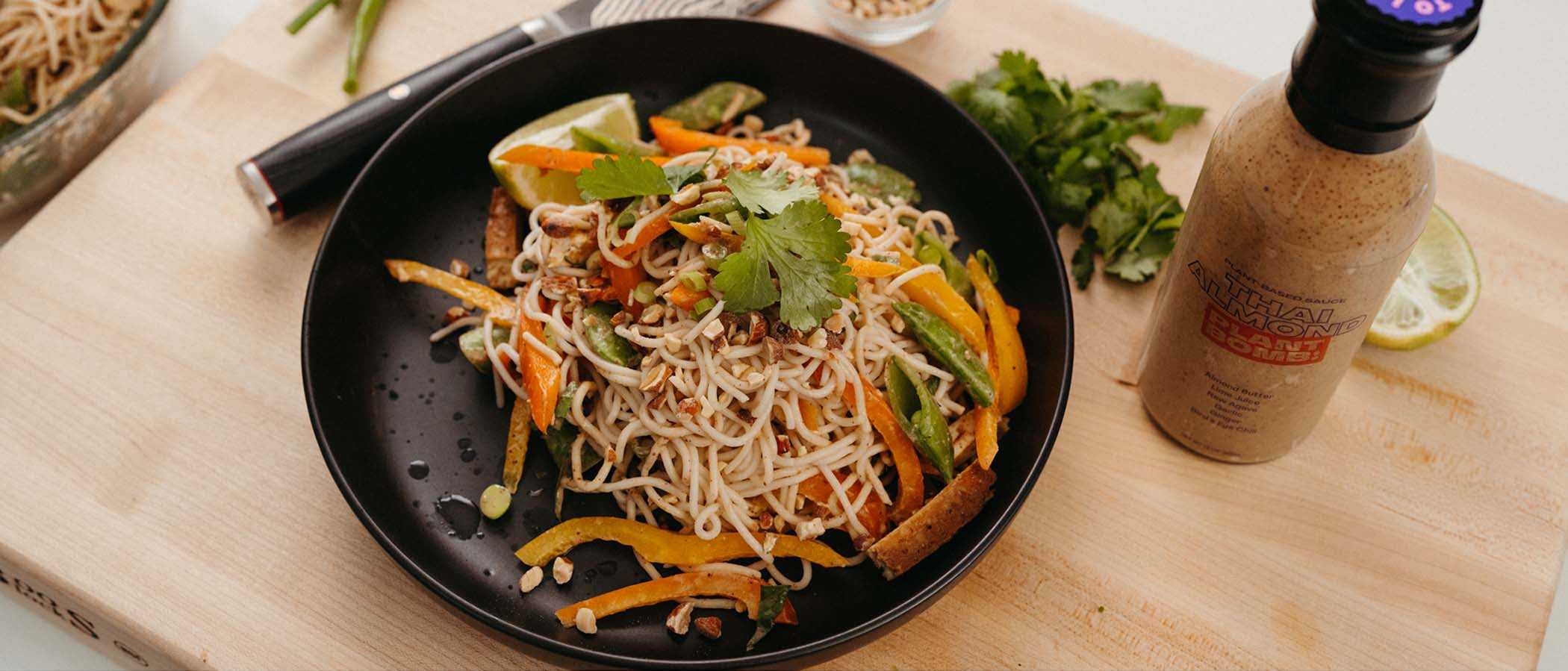 Thai Almond Cold Noodle Salad in bowl with sauce next to it.