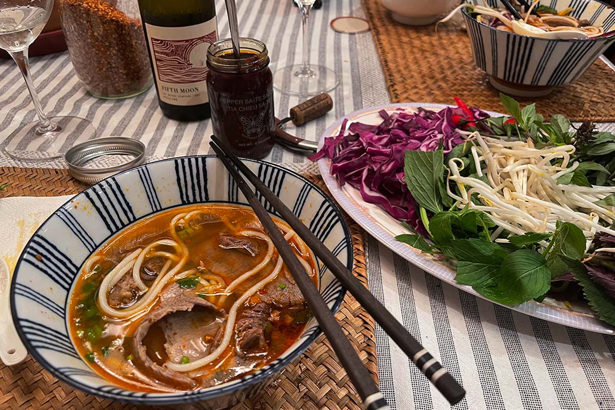 Table set with noodle soup and chopsticks on side of bowl