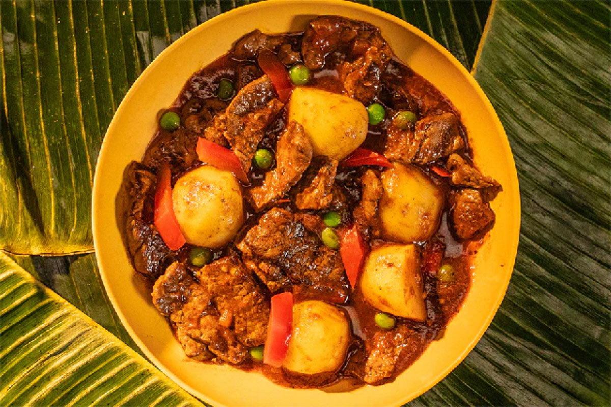 Yellow bowl of caldereta on banana leaves