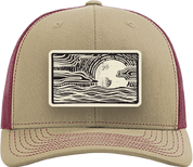 A tan and burgundy trucker cap featuring a rectangular front patch with a black and white wave pattern and a central white circle.