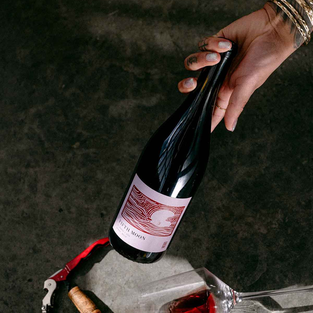 Hand reaching for a Fifth Moon wine bottle