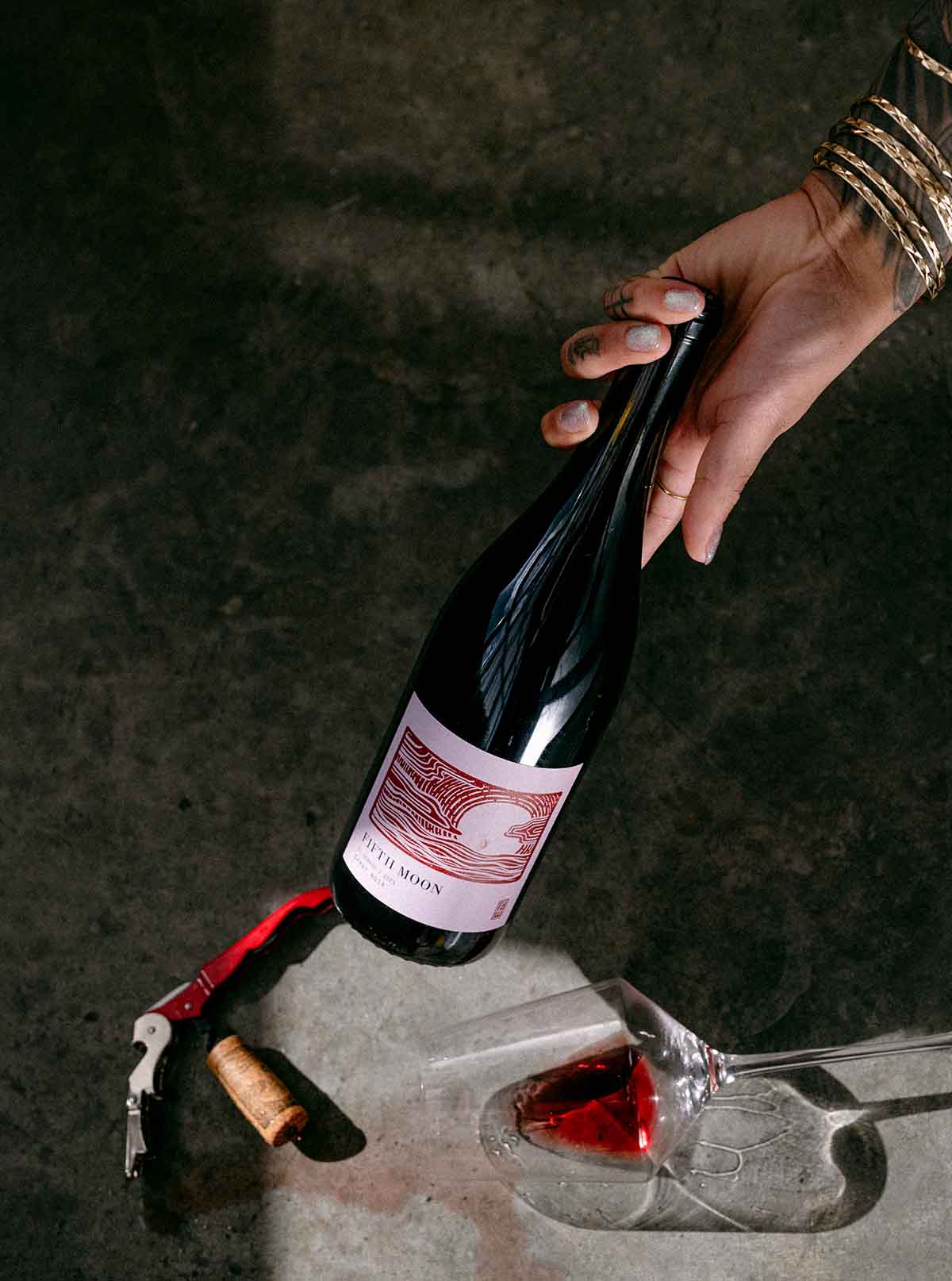 Hand reaching for a Fifth Moon wine bottle