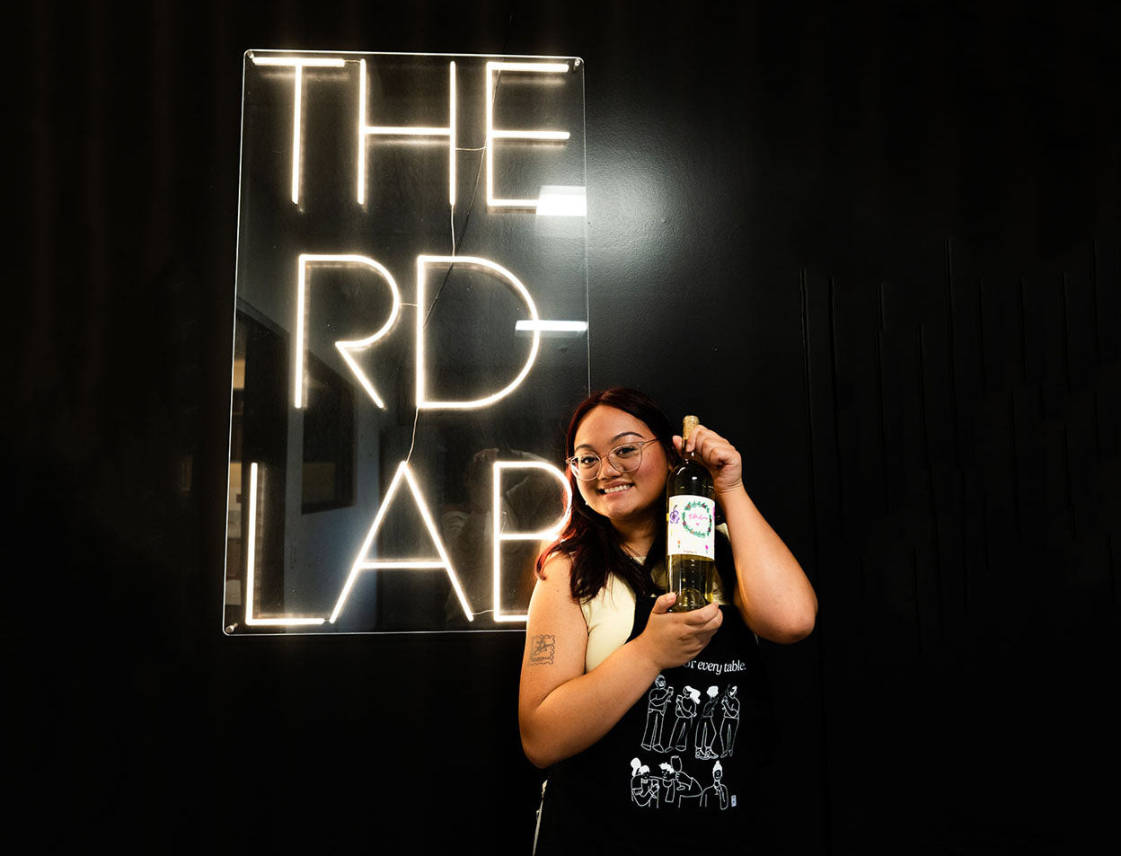 Guest holding her custom bottle at the RD Lab neon sign