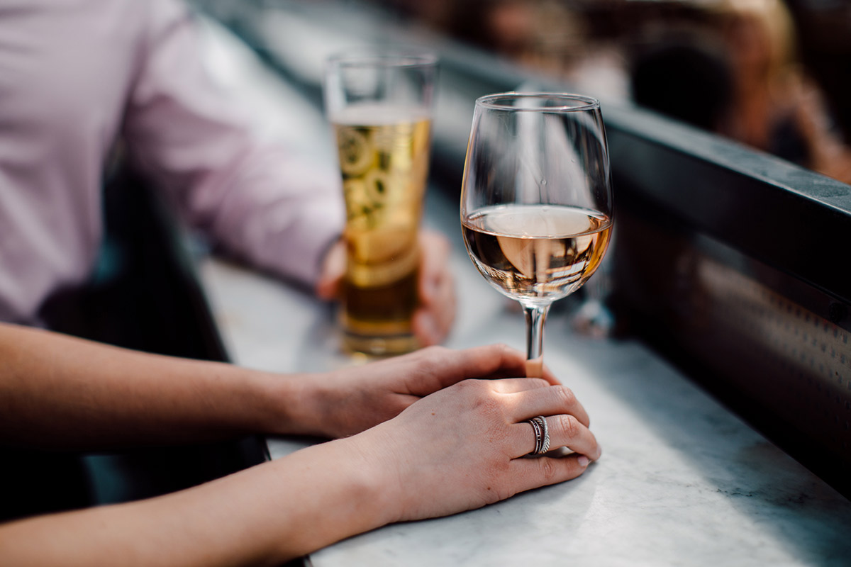 Hand holding glass of rosé and hand holding glass of beer