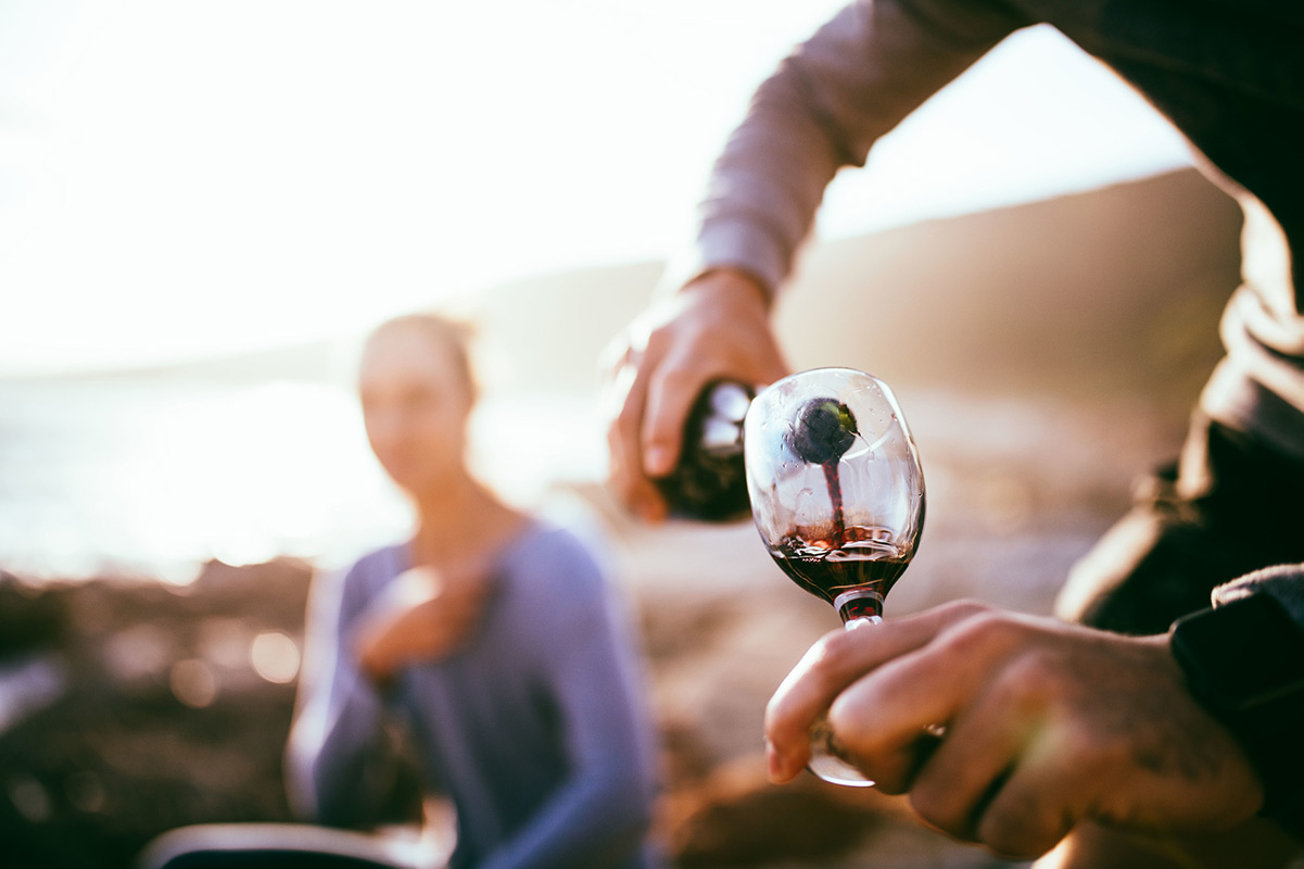 Guy pouring wine for girl at the beach