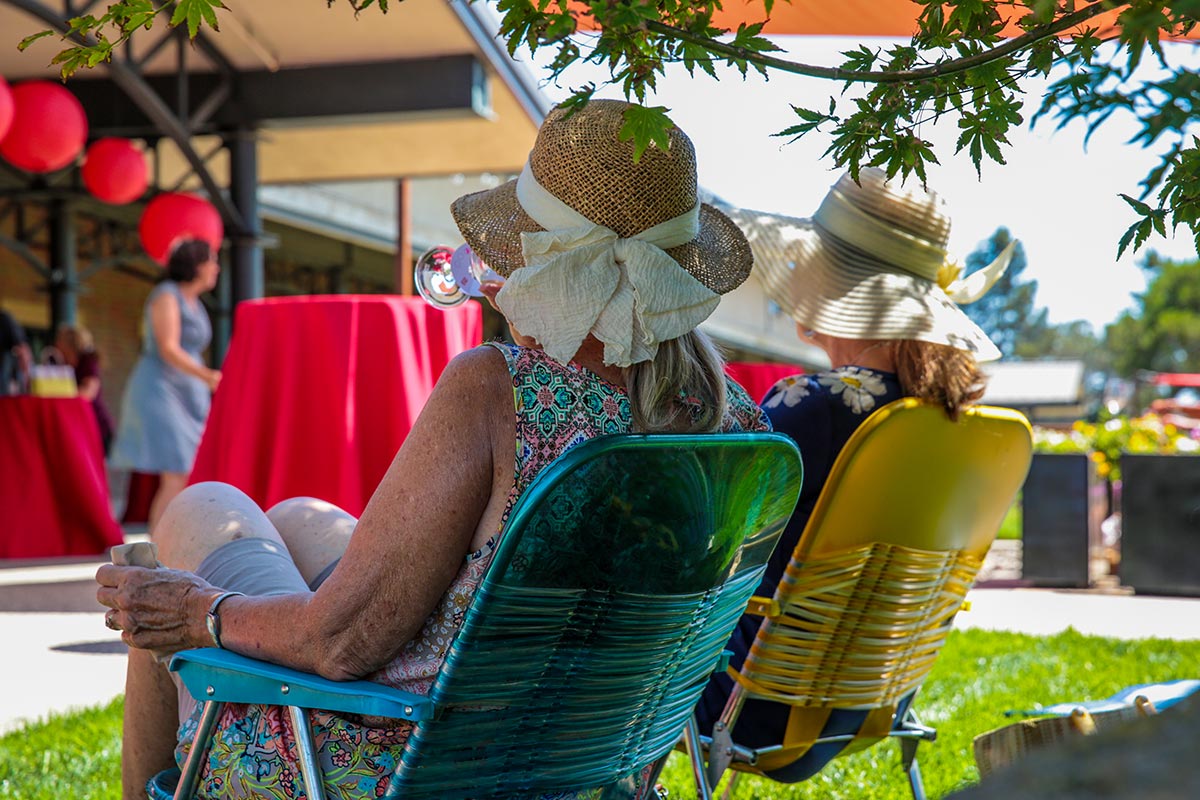 Women in hats sitting in lawn chairs