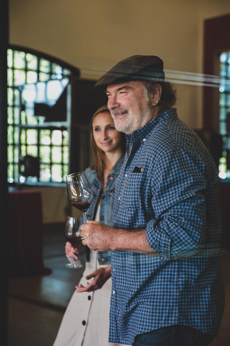 Older man in hat holding wine glass and smiling