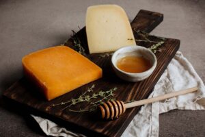 Hard cheeses on a wooden board with honey.