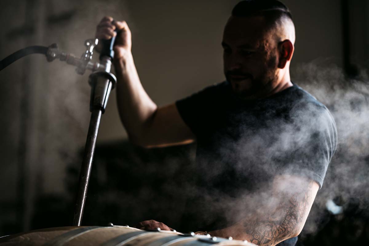 Darkly lit man cleaning barrels