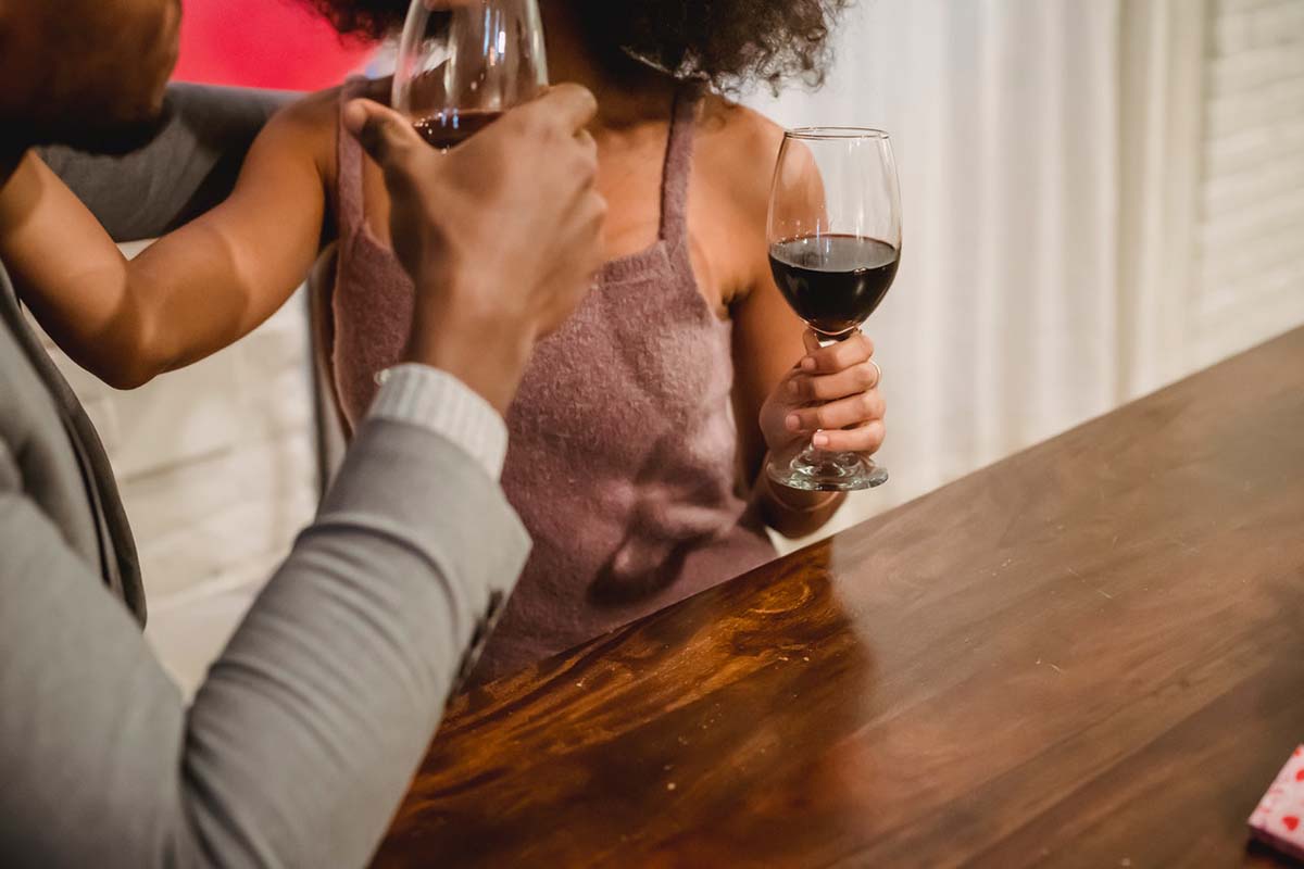 A couple getting close at the bar with wine in hand