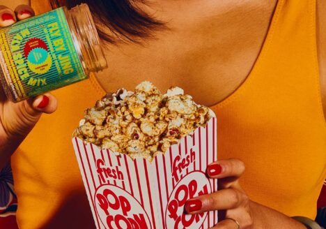 Close up of woman seasoning popcorn with Fly By Jing Mala Spice Mix