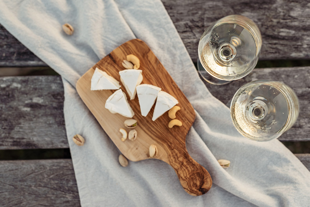 Overhead shot of two glasses of white wine next to a cheese board.