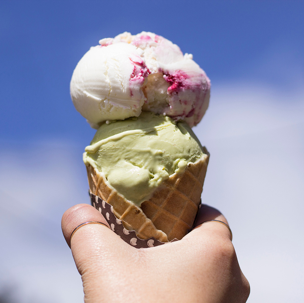 Hand holding cone with two scoops of ice cream