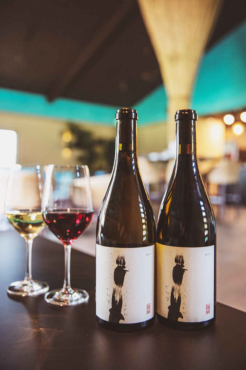 Bottles of Khoai Pinot Noir and Chardonnay on table in tasting room