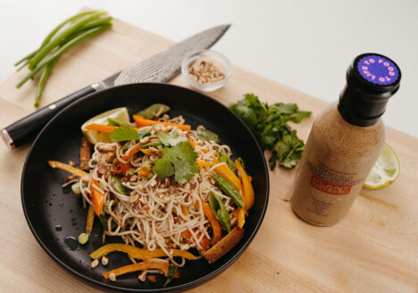 Thai Almond Cold Noodle Salad in bowl with sauce next to it.