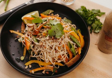 Thai Almond Cold Noodle Salad in bowl with sauce next to it.