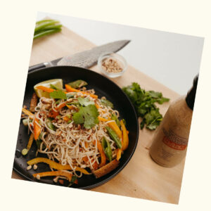 Thai Almond Cold Noodle Salad in a bowl with Plant Bomb sauce bottle