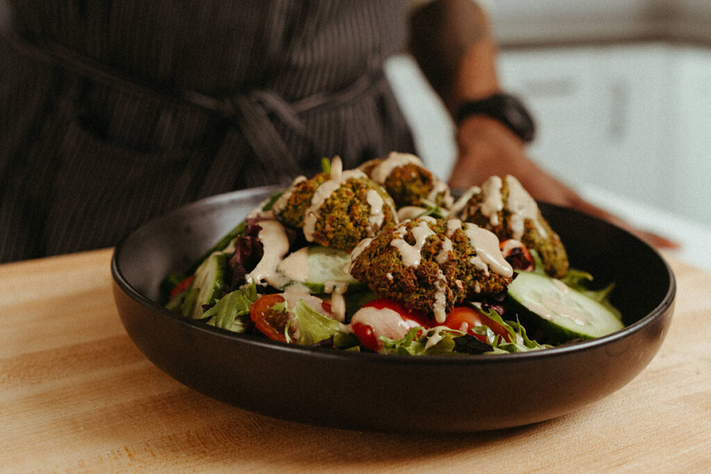 Bowl of salad topped with falafel and garlic tahini dressing