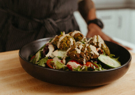 Bowl of salad topped with falafel and garlic tahini dressing