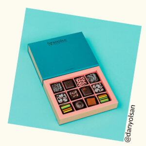 Box of colorful chocolate truffles on a turquoise background