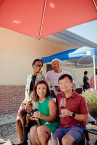 Four guests and a dog sitting on outdoor patio with wine