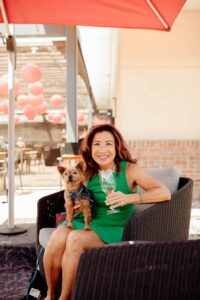 Woman in a green dress with a dog on her lap