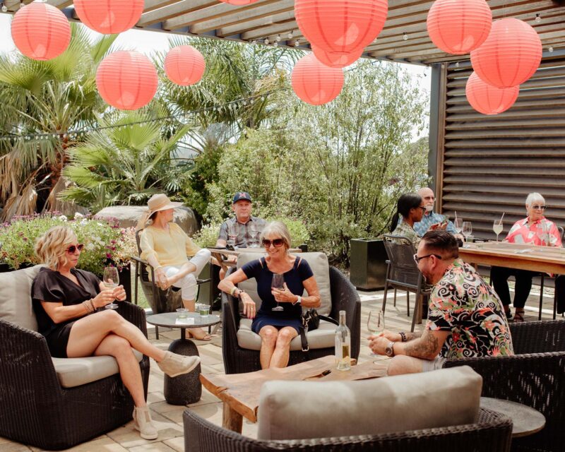 Group of guests relax on patio under red lanterns