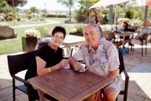 A couple sits smiling at patio table with wine