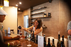 Winery staff member pours red wine for guest at bar