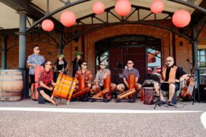 A Polynesian band with many members smiles