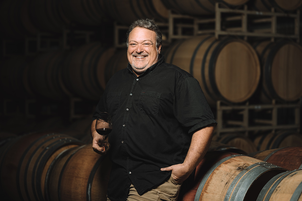 winemaker smiling in front of barrels