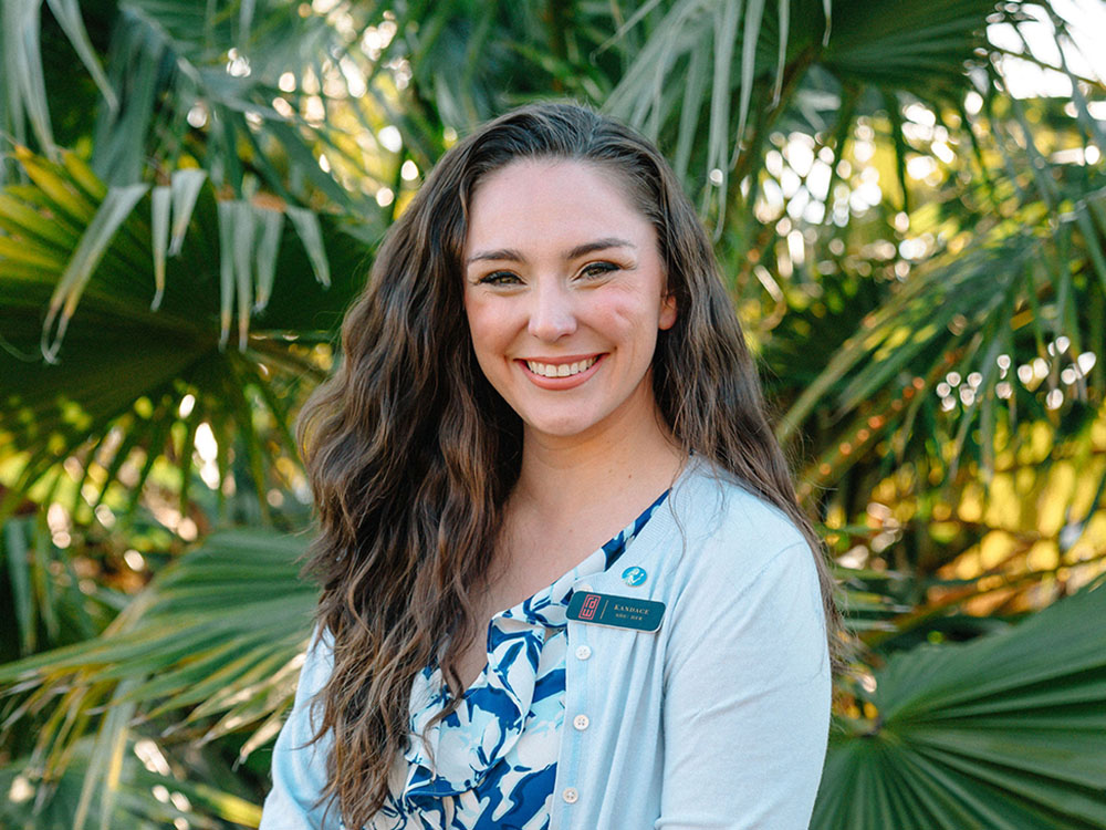 kandace-markovich-headshot-25 Kandace headshot in front of palm leaves